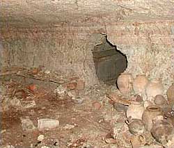 Erster Blick in die Hauptkammer der königlichen Grüfte. Man erkennt steinerne Bänke an den Kammermauern, auf denen Gefäße aus Keramik und Alabaster abgestellt sind. Der Durchgang zu einer der Nebenkammern erlaubt einen Blick auf den zweiten bisher entdeckten steinernen Sarkophag. (Photo: Konrad Wita, Berlin)